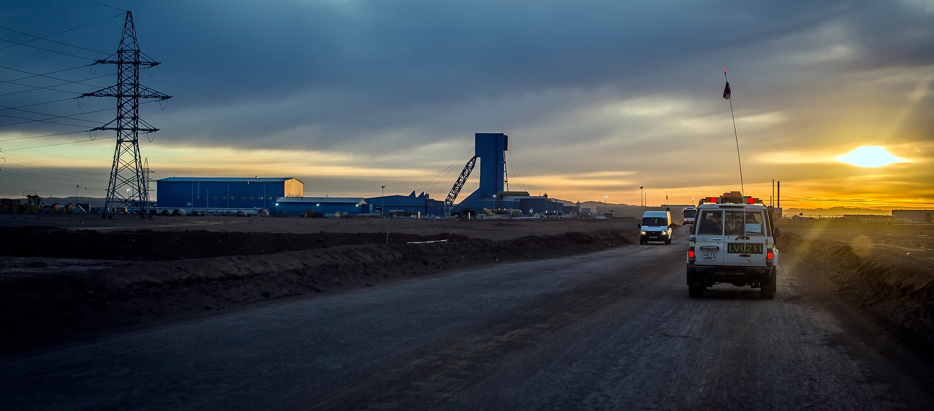 Industrial site at sunset with vehicles and plant infrastructure